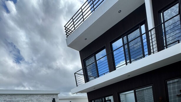Um edifício moderno com piscina, espreguiçadeiras e vista para o mar.