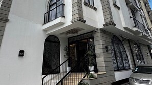 A multi-story building with a modern architectural design, featuring a prominent entrance with a staircase, a metal railing, and a car parked in front. - Cozy Stay + breakfast 201 (Addis Ababa)
