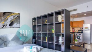 Una habitación de hotel moderna con una cama grande, un armario empotrado, una pequeña cocina y un baño.