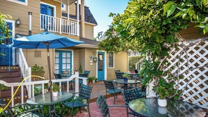 A patio area with outdoor seating, including tables and chairs, and a blue umbrella. - Bath Street Inn B & B, Santa Barbara (Santa Barbara)