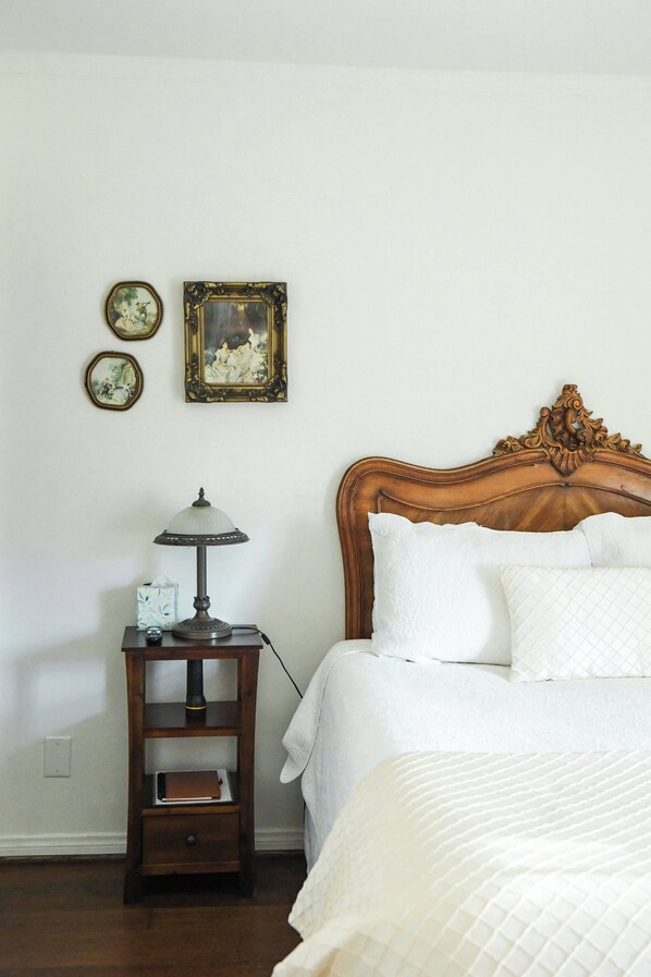 A bedroom with a wooden headboard, a bedside table with a lamp, and two framed pictures on the wall.