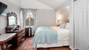 A bedroom with a bed, a dresser, a desk, a mirror, a window with curtains, and a patterned rug. - Bath Street Inn B & B, Santa Barbara (Santa Barbara)