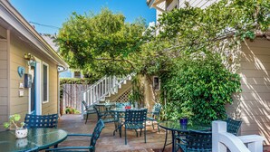 Un patio couvert avec des meubles d’extérieur, une terrasse en bois et une vue sur une rue résidentielle.