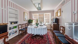 Un coin repas avec une table ronde, des chaises, un tapis à motifs et un papier peint à rayures.