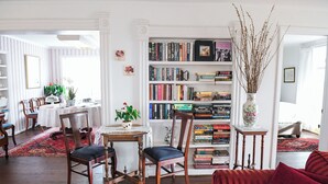 Un salon chaleureux avec une bibliothèque, un coin repas comprenant une table et des chaises, et un canapé rouge.