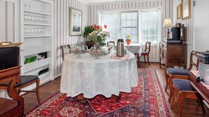 A dining area with a table set for four, surrounded by chairs, a coffee station, and a bookshelf. - Bath Street Inn B & B, Santa Barbara (Santa Barbara)