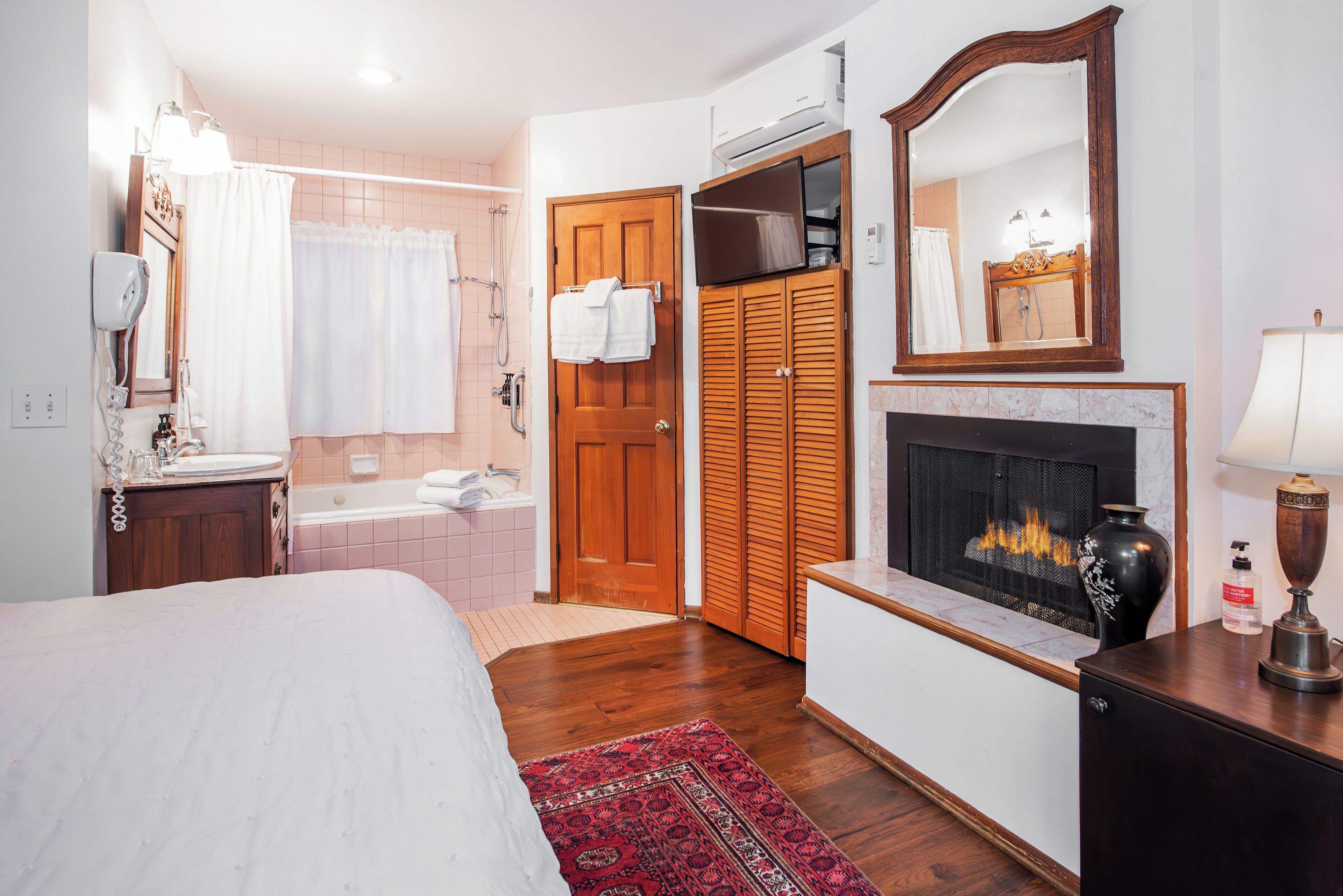 Une chambre avec un lit, une salle de bain avec une baignoire, une cheminée et une armoire.