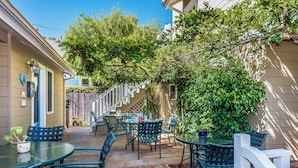 A covered patio with outdoor furniture, a wooden deck, and a view of a residential street. - Bath Street Inn B & B, Santa Barbara (Santa Barbara)