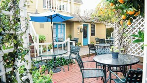 A patio area with outdoor seating, a blue umbrella, and a white fence. - Bath Street Inn B & B, Santa Barbara (Santa Barbara)