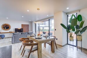 Relax in this stylish living area with a glass-top dining table, comfortable sofa, and beautiful views of the outdoors.