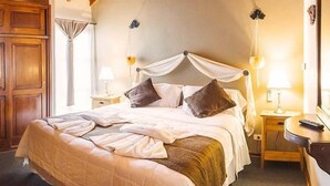 A neatly made bed with a canopy, a bedside table with a lamp, and a wooden wardrobe. - Rotui Apart Hotel (San Martín de los Andes)