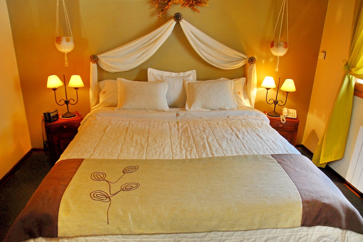 A bed with a canopy, two bedside lamps, and a decorative wall hanging.