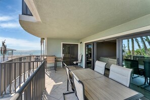Enjoy a comfortable seating area with a view of the beach from this spacious balcony, featuring a table and chairs.