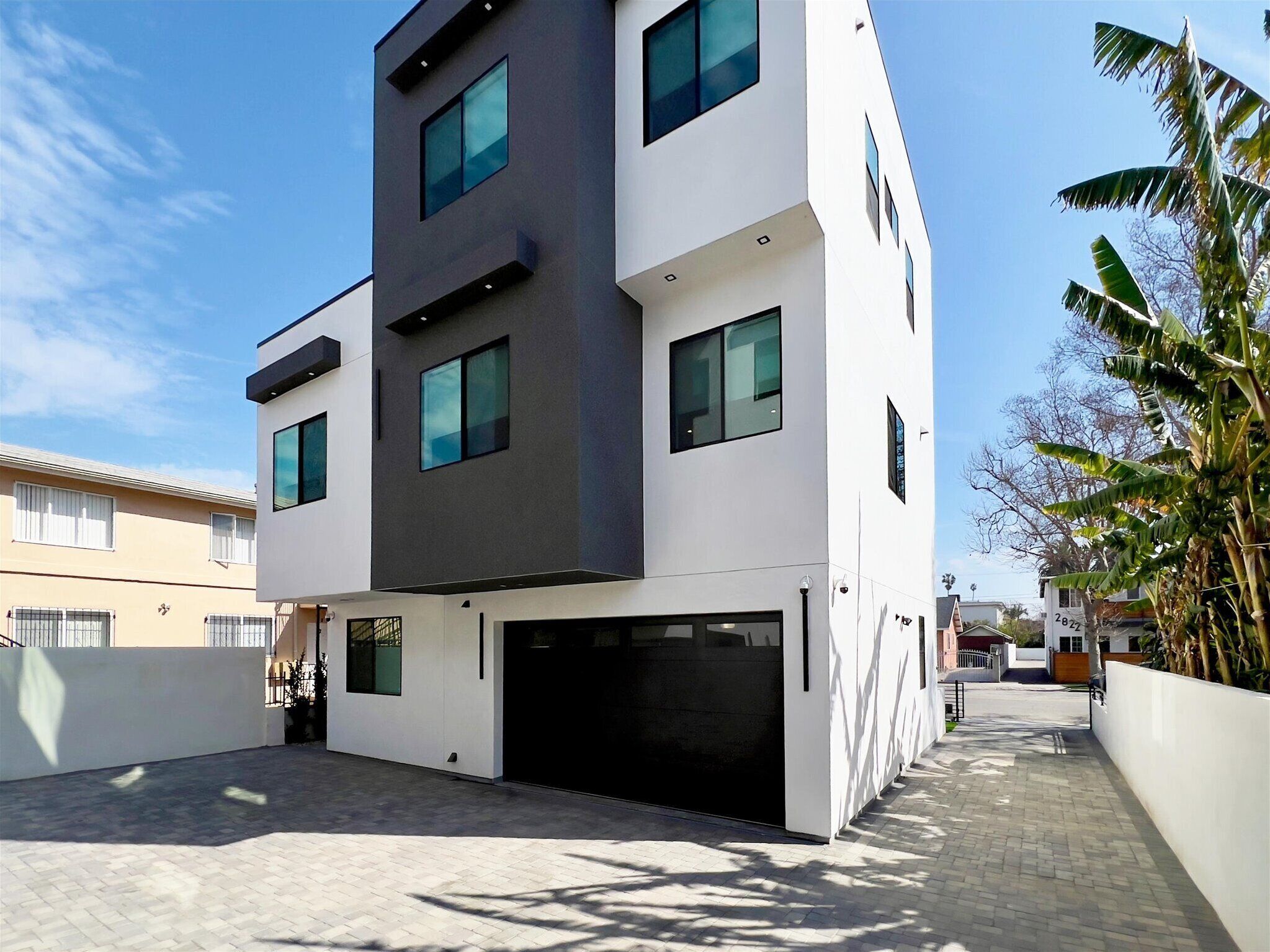A modern two-story building with a flat roof, large windows, and a garage.