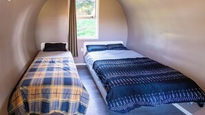 A small, curved room with two beds, a window, and a geometric light fixture. - Morning Calm Lodge Limited (Hamilton)