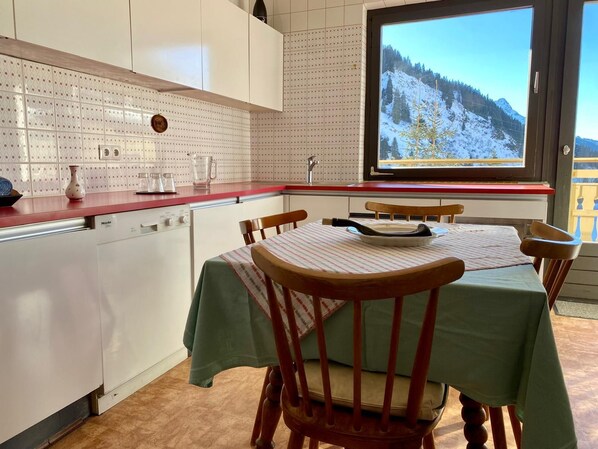 Una cocina con una mesa de comedor, sillas y un ventanal con vista a la montaña.