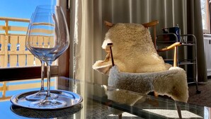 A room with a glass table, a fluffy chair, and a view of a balcony. - Arlberg Motel (Klösterle am Arlberg)