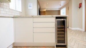 A modern kitchen with white cabinetry, a built-in oven, and a glass-fronted refrigerator. - Bath Bliss Retreat - 7 Bedroom House (Bath)