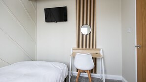 A bedroom with a bed, a desk with a chair, a TV, and a mirror. - Bath Bliss Retreat - 7 Bedroom House (Bath)