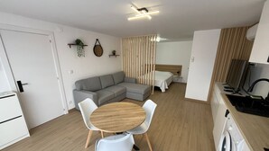A modern, compact living space with a dining area, kitchenette, and a bed. - Sublime, cosy and functional studio between braga and gêres (Bico)