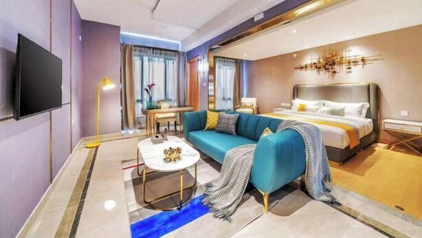 Ett modernt hotellrum med en soffa, en säng, en tv och ett litet bord.