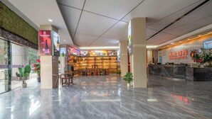 En hotellobby med en receptionsdisk, en sittgrupp och en entré med glasfasad.