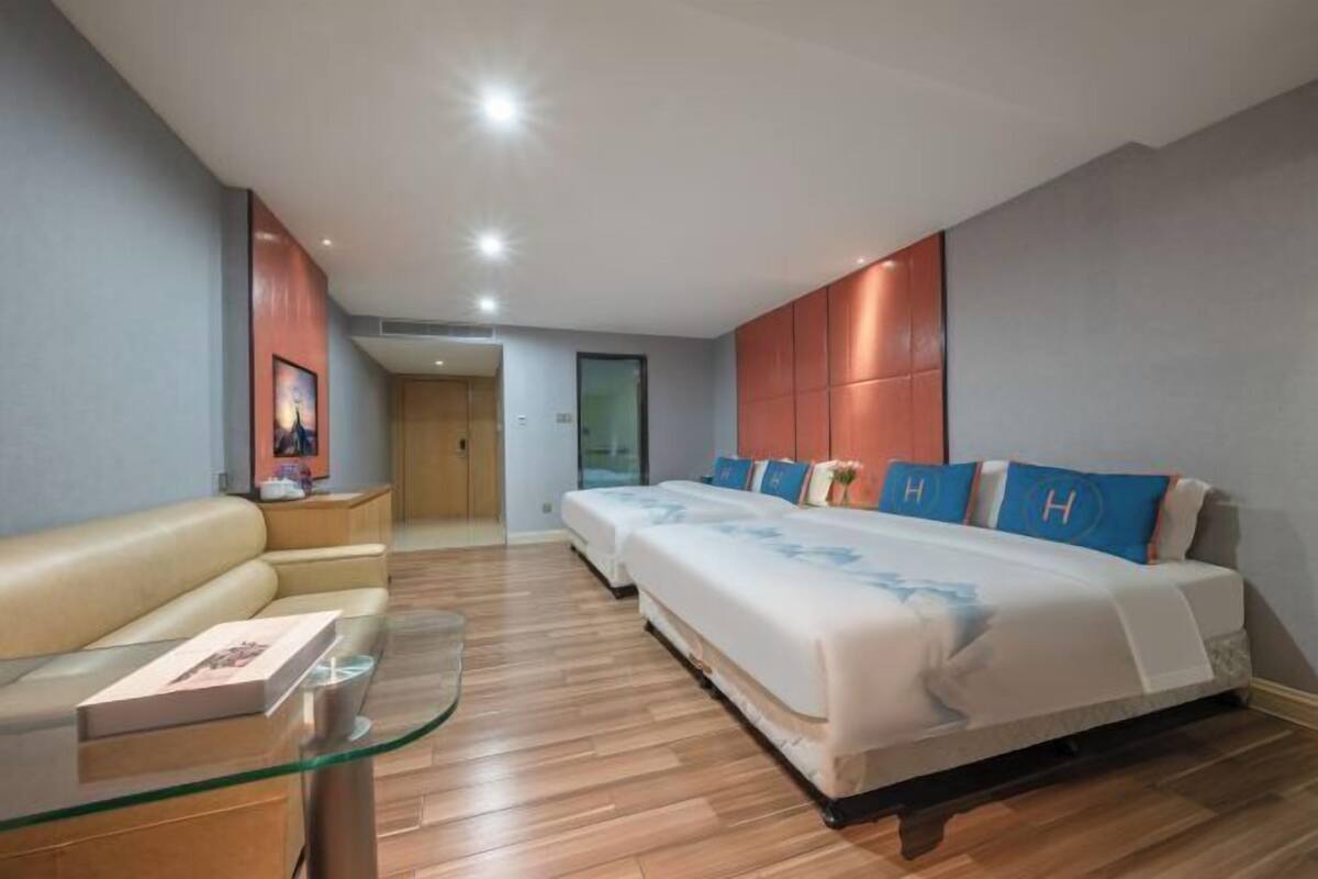 Une chambre d’hôtel avec un lit, une table en verre, un canapé et une porte donnant sur une autre pièce.