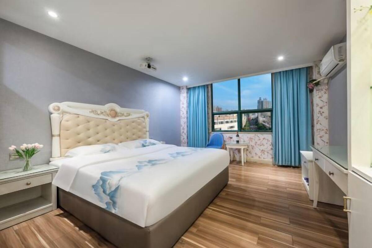 Une chambre d’hôtel avec un grand lit, un bureau, une chaise et une vue sur la ville.