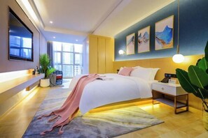 Una habitación de hotel moderna con una cama grande, mesita de noche y televisor montado en la pared.