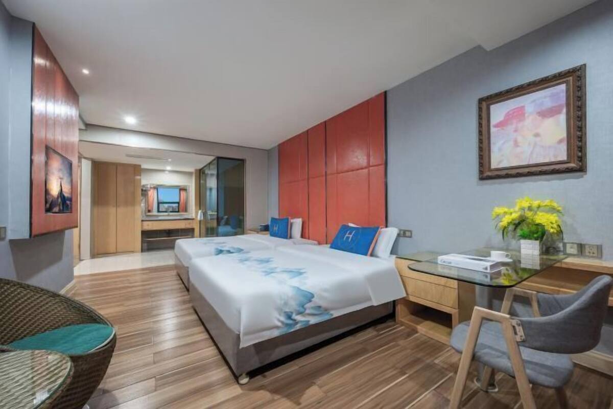 Une chambre d’hôtel moderne avec un grand lit, un bureau, une chaise et une table en verre.