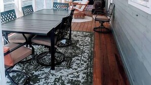 A covered patio with a wooden table and chairs, a patterned rug, and a seating area with cushions. - Spacious Pawtuckaway Getaway (Nottingham)