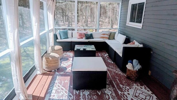 A cozy room with a large window, a cushioned seating area, and a patterned rug. - Spacious Pawtuckaway Getaway (Nottingham)