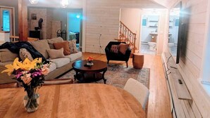 A spacious living room with a sofa, coffee table, and a TV mounted on the wall. - Spacious Pawtuckaway Getaway (Nottingham)