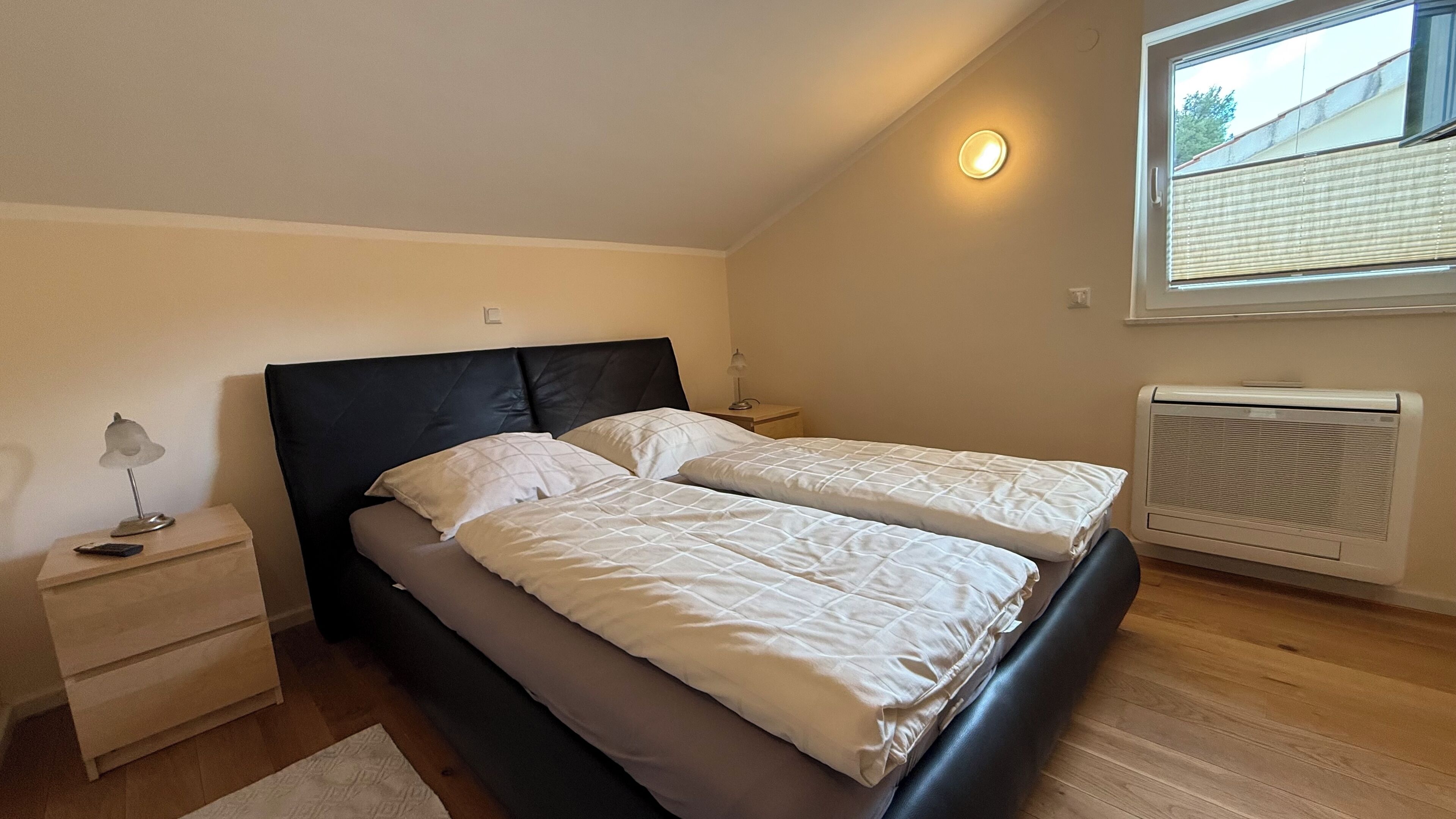 A bedroom with a bed, bedside tables, a lamp, a window, and a radiator.