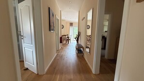 A hallway with wooden flooring, white walls, and doors leading to other rooms. There is a dining area with a table and chairs visible in the distance. - Enjoy KRK waterfalls, sun, beach and sea: Domicile Sunce Krka Studio (Skradin)