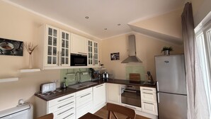 A modern kitchen with white cabinetry, a stainless steel refrigerator, a microwave, and a large oven. - Enjoy KRK waterfalls, sun, beach and sea: Domicile Sunce Krka Studio (Skradin)