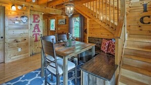A wooden cabin interior with a dining table, chairs, a chandelier, and a staircase. - Awesome Private Mountain views Resort Pool &HotTub (Sevierville)