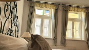 A hotel room with a bed, a lamp, and curtains. - Hotel zur Post (Wernigerode)