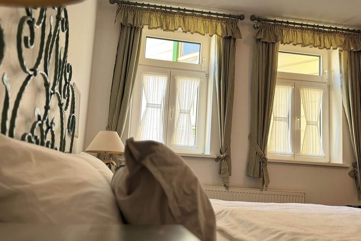 Ein Hotelzimmer mit Bett, Lampe und Vorhängen.