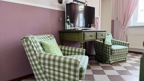 A room with a checkered green and white sofa, a matching armchair, and a small table with a mirror and bottles. - Hotel zur Post (Wernigerode)