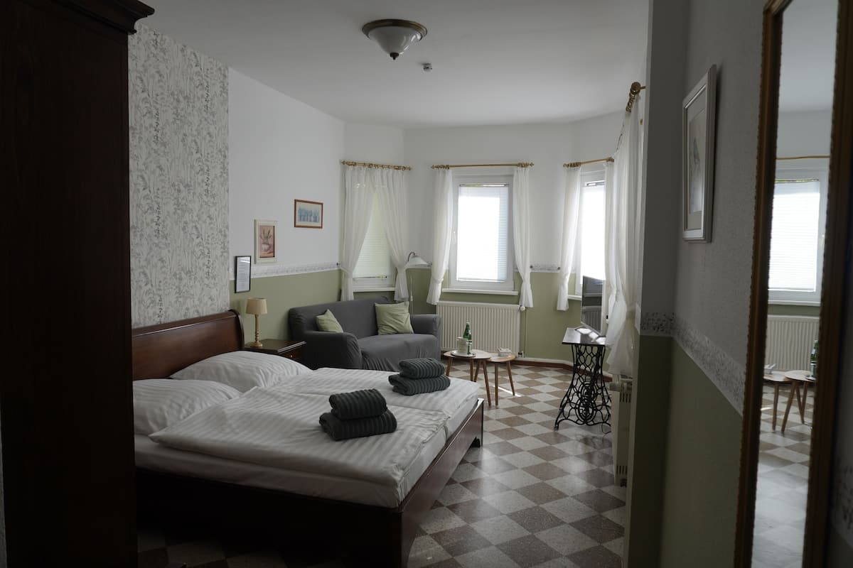 Ein Hotelzimmer mit zwei Betten, einem Schlafsofa, einem kleinen Tisch und einem Sessel.