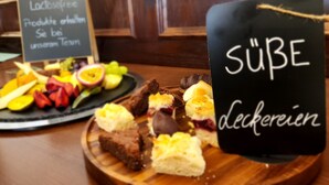 A dessert display with various sweets and fruits, including a sign with text in a foreign language. - Hotel zur Post (Wernigerode)