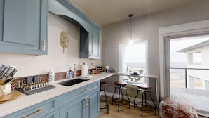 Una cocina con armarios azules, un lavamanos y taburetes de bar.
