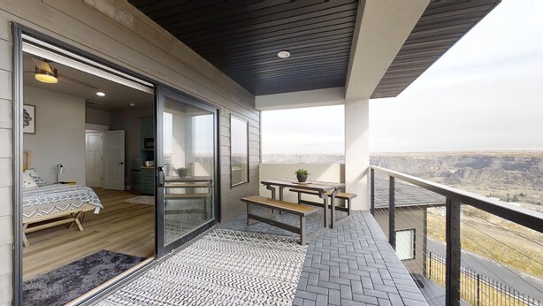 Un balcón con piso de madera, un tapete estampado y vista a un cañón.