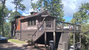 A two-story house with a covered porch, a staircase, and a small garden area. - Beautiful Mountain Views with your own private hot tub! (Cashiers)