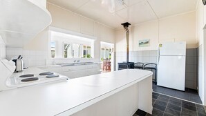A modern kitchen with white cabinetry, a large island, a built-in stove, and a refrigerator. - The Narooma Escape (Narooma)