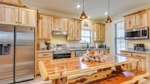 A kitchen with wooden cabinets, stainless steel appliances, a wooden island, and pendant lighting.