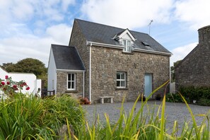 A stone house with a sloped roof, a small porch, and a gravel driveway. - Two Hoots - Peaceful Cottage Rural Views (Pembroke)