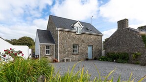 A stone house with a gravel driveway, a small garden with flowers, and a clear sky. - Two Hoots - Peaceful Cottage Rural Views (Pembroke)