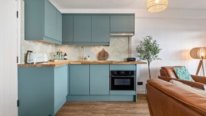 A modern kitchen with teal cabinets, a wooden countertop, and a built-in oven. - Beach Retreat - Sea Views Parking Beach Access (Saundersfoot)